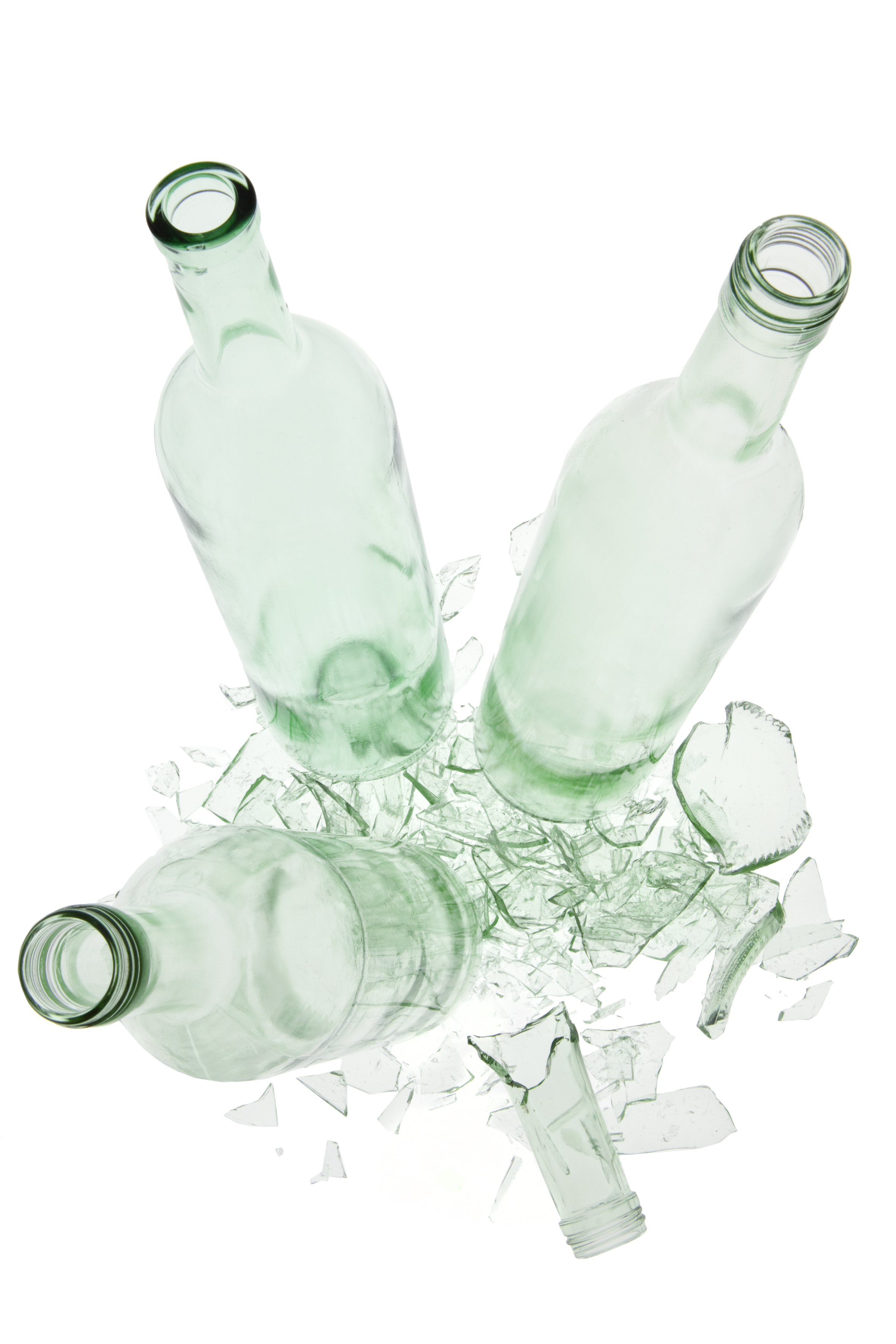 Drei hellgrüne leere Glasflaschen stehen auf den Scherben einer vierten hellgrünen Glasflasche.