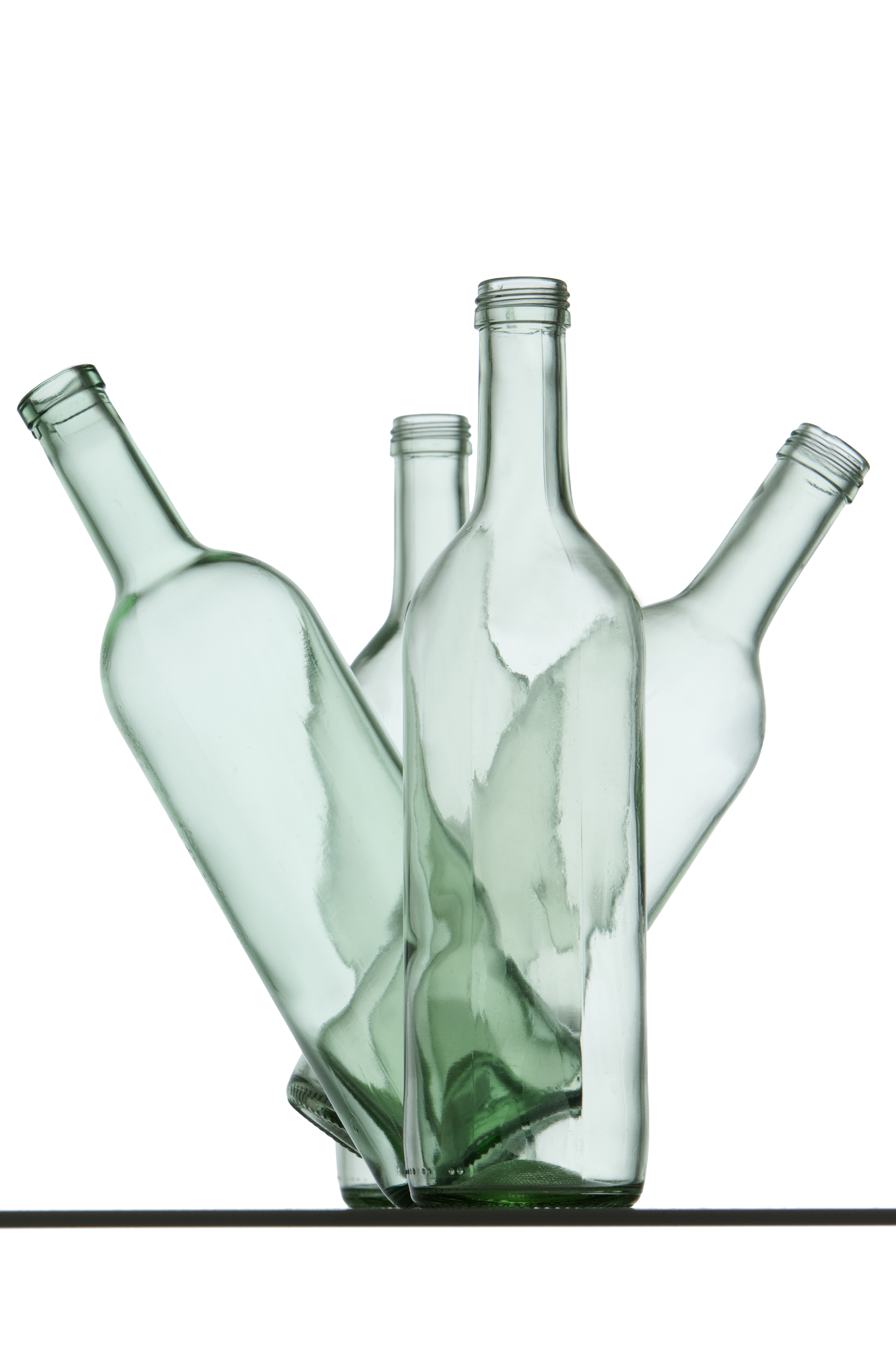 Vier hellgrüne Glasflaschen stehen so zueinander, dass es aussieht, als ob sie tanzen.