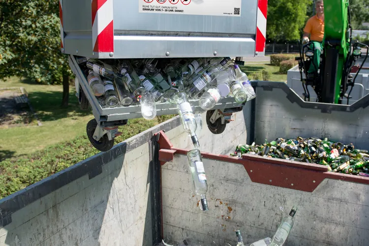 Leere Weißglasverpackungen werden aus einem Container in einen großen Sammelbehälter entleert